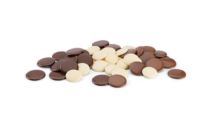 Dark, White, and Milk chocolate sit in a pile against a white backdrop. 