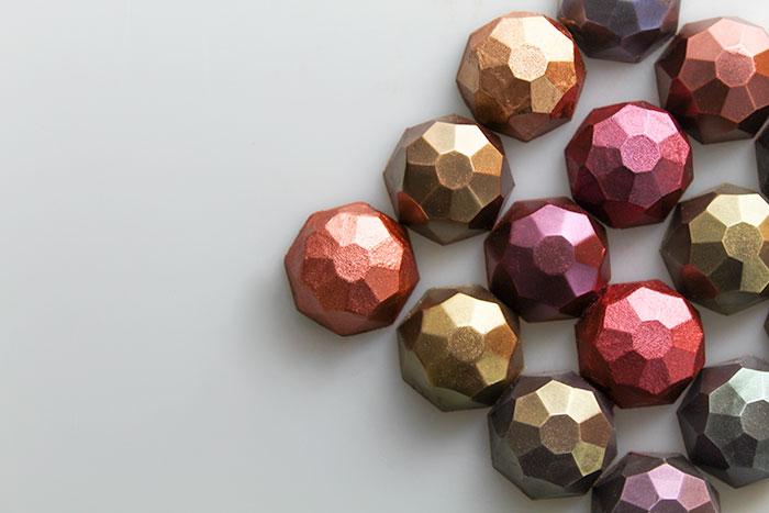 Shiny, multicolored bon bons sit in a horizontal v shape to the right of the image against a light gray background. 